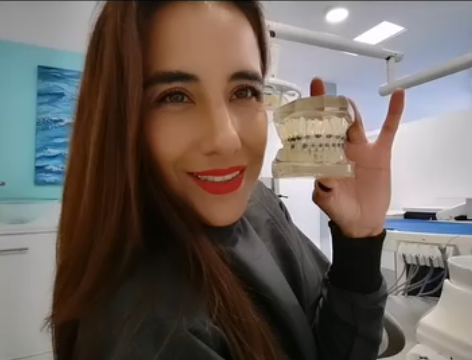 Dra. Elizabeth Baltazar sosteniendo un modelo dental con brackets para explicar el tratamiento de ortodoncia